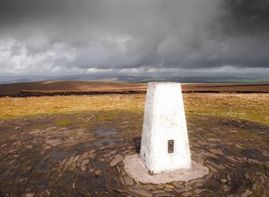 Trig point on top of Pendle Hill under a lowering sky.