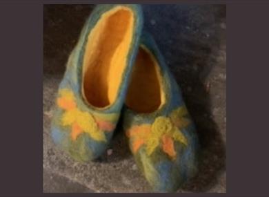 A pair of grey felt slippers with a flower pattern.