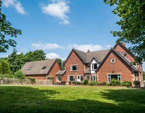 Outside view of the farmhouse, set in the countryside, on a bright sunny day.