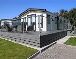 Caravan with grey decking and glass fence