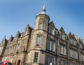 The Grade Two listed Storey building made of sand coloured stone with tall Georgian windows, and a tower with spire.