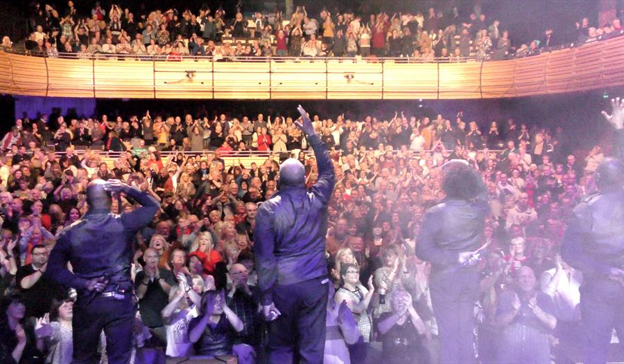 The performers are interacting with their fans in a full theatre of adoring fans.