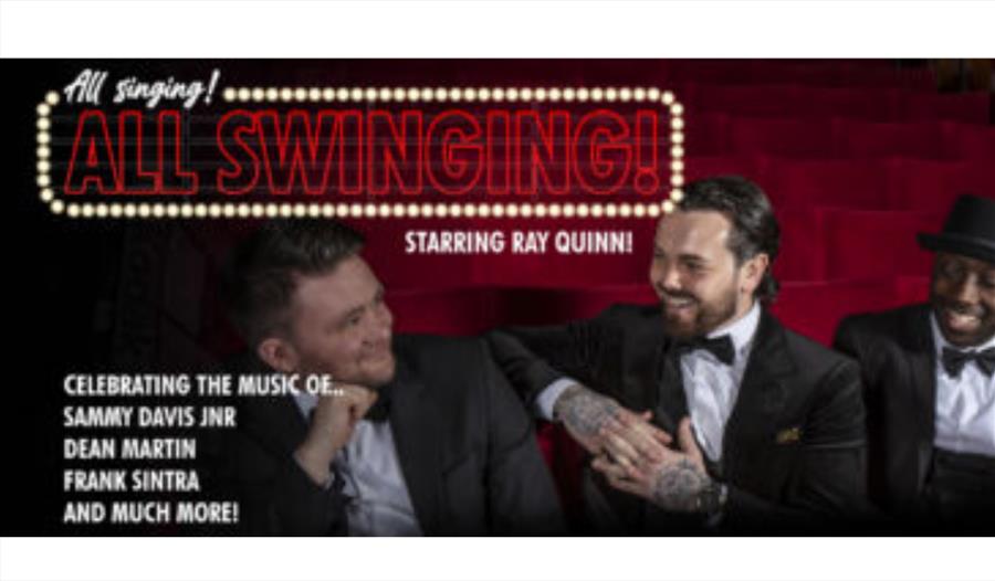 Ray and the band sat on red theatre chairs in formal dress.