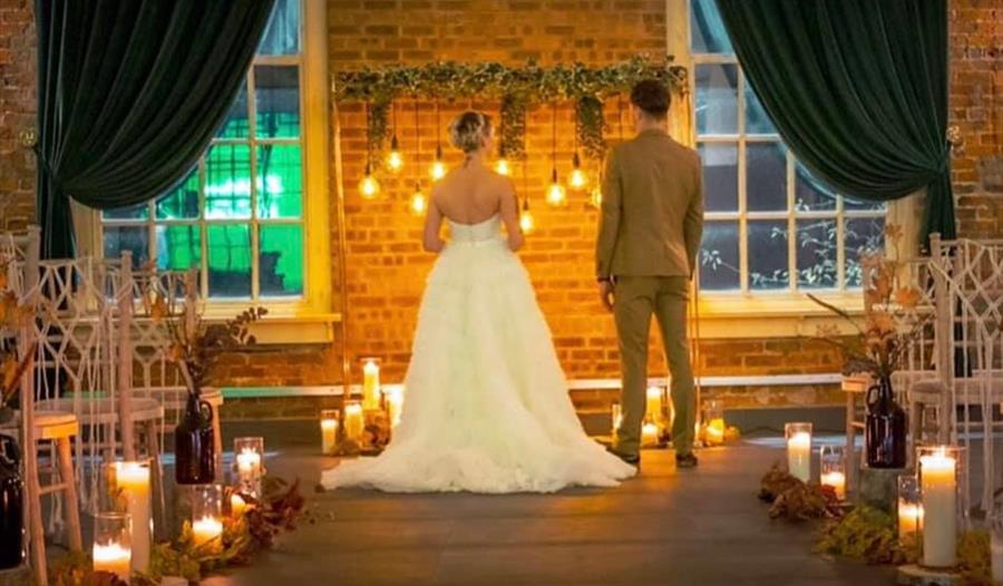 A couple stand in the venue with candles and lights decorating.