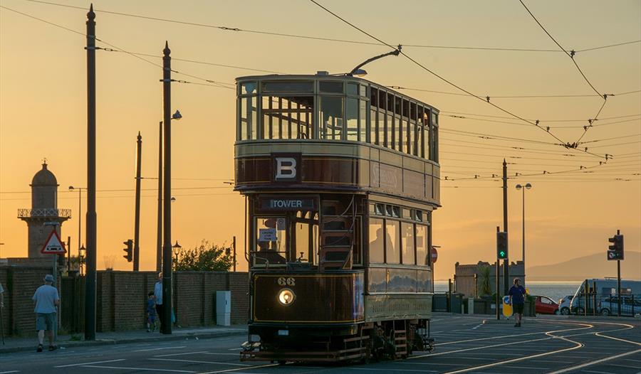A heritage tram rides through Blackpool at sunset.