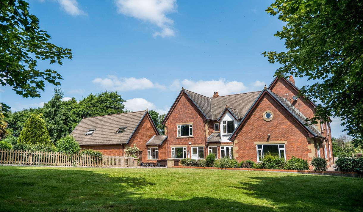 Outside view of the farmhouse, set in the countryside, on a bright sunny day.