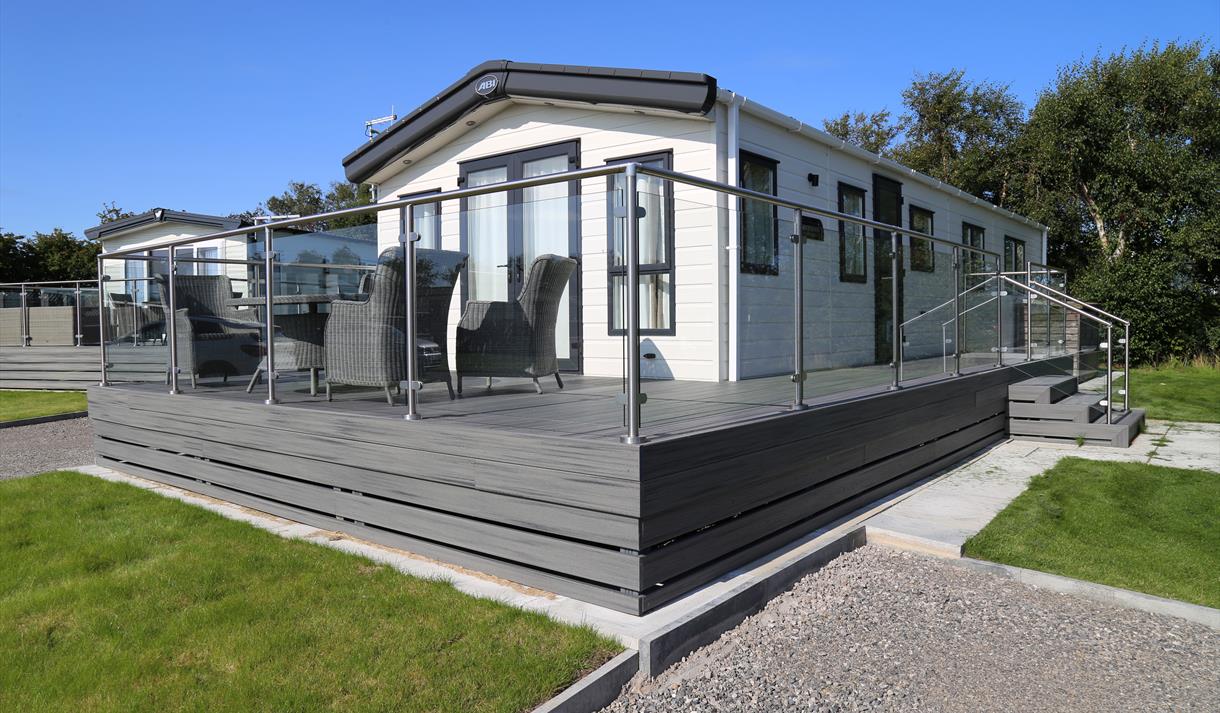 Caravan with grey decking and glass fence