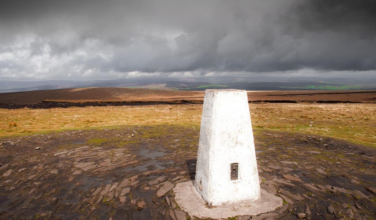 Trig point on top of Pendle Hill under a lowering sky.