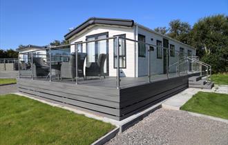 Caravan with grey decking and glass fence