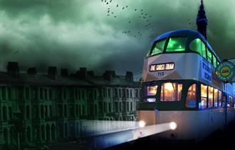 A heritage tram travels through Blackpool, past the Blackpool Tower.  Headlights are on and spooky bats fly in the eyry sky.