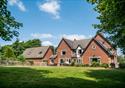 Outside view of the farmhouse, set in the countryside, on a bright sunny day.