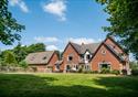 Outside view of the farmhouse, set in the countryside, on a bright sunny day.