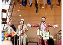 Two colourfully dressed men perform on a stage.