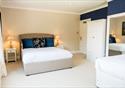 The bedroom within the farmhouse with white linen and furniture.