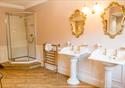 View of the farmhouse bathroom with two sinks and gold decorative mirrors.