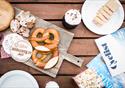 An inviting spread of food with cheese and pretzels.  Travel guides and magazine await their reader.