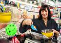 A lady with warm brown hair dishes out pick and mix sweets into a weighing scale
