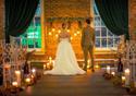 A couple stand in the venue with candles and lights decorating.