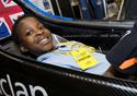 A young boy sits in a racing car.
