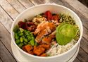 Bowl of colourful food on a wooden bench.