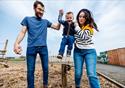 A couple help a child leap with joy at the farm.