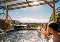 A couple enjoy the hot tub, with a glass of fizz, on sunny day.
