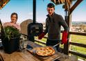 A couple enjoy cooking together, making a pizza for two.