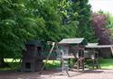 A children's play area surrounded by trees and woodland.  Wooden structures for plenty of adventures.