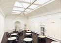 Round tables are dotted around a light, bright room with glass roof and historic detailing, including a statue of Queen Victoria and Price Albert
