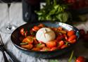 A colourful salad in a black bowl awaits a diner.