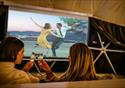 Guests watch a movie on the pull down projector screen, while enjoying a glass of fizz.
