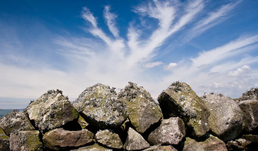 Dry stone wall with blue sky and clouds.