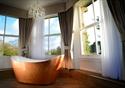 Copper bath in front of windows overlook gardens