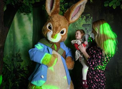 A child and her mother is delighted to meet Peter Rabbit.
