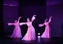 Three dancers perform on stage in beautiful pink dress.