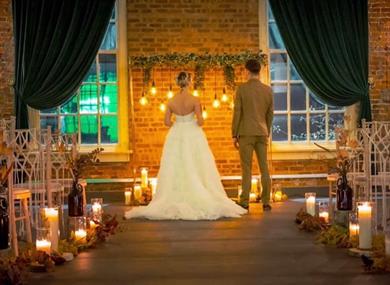A couple stand in the venue with candles and lights decorating.