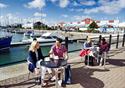 Two sets of couples sit on the marina at Affinity Lancashire, with their shopping bags at their feet, enjoying a relaxing break with a coffee.