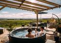 A couple enjoy a hot tub, with a glass of fizz, in the sunshine.  A beautiful panoramic view of Lancashire awaits guests.