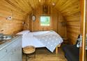 A comfortable bed awaits in a wooden glamping pod.