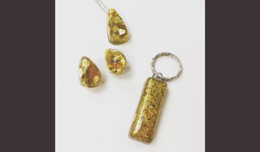 Three pieces of jewellery - a necklace, earrings and a keyring with a yellow colour.