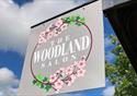 A welcoming sign for the Woodland Salon with a pink flower design.
