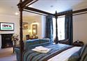 Four poster bedroom with roaring fire at The Villa Country House Hotel