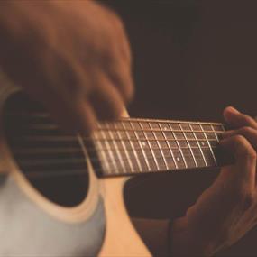 Person playing acoustic guitar with a capo