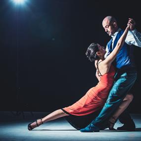 A woman in a red dress and her dance partner holding her