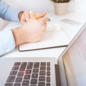 White laptop and man writing in notebook