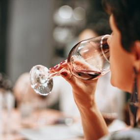 A person drinking from a clear wine glass