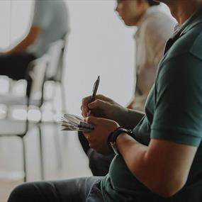 Person sitting in a chair taking notes on paper