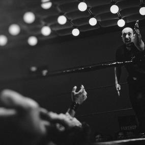 Wrestler down in the ring and referee gesturing with arm