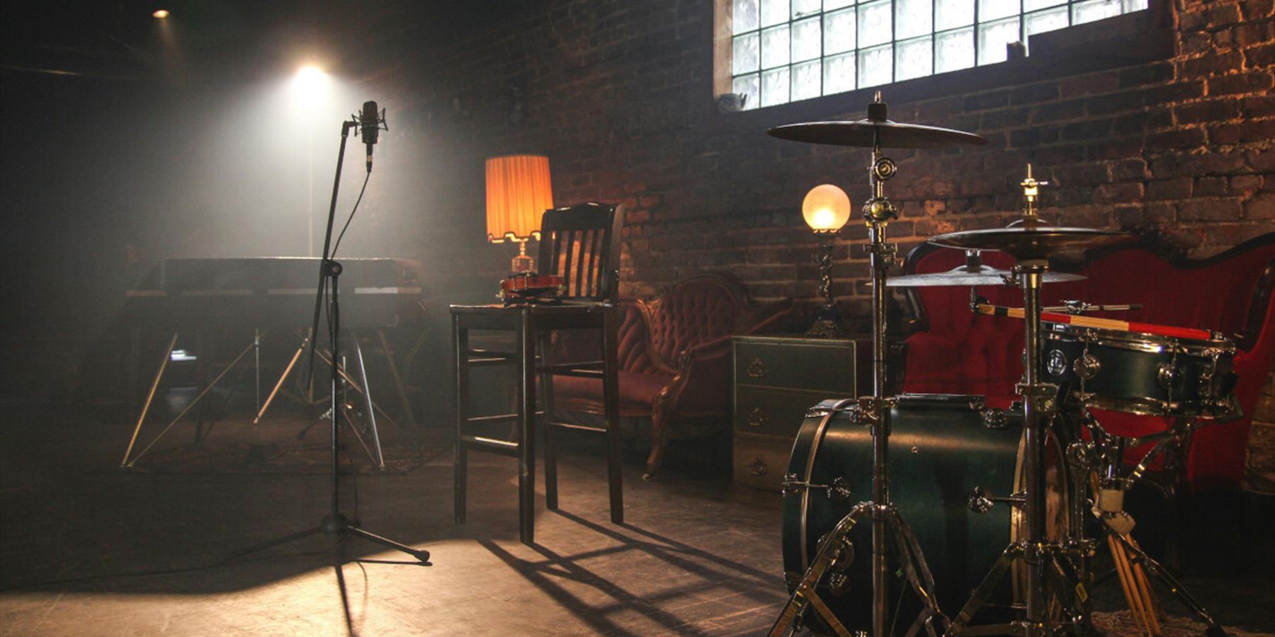 Microphone and drum kit in warmly lit room