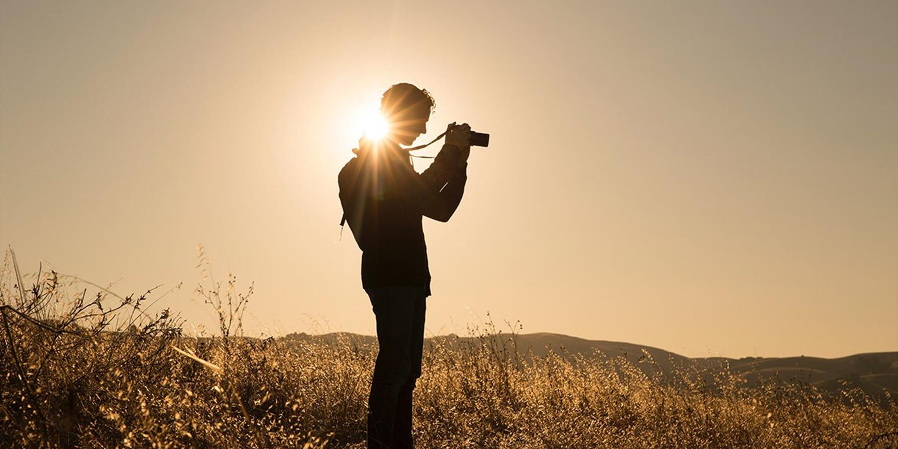 Person taking photographs in an empty field